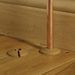 Wooden Flooring with a copper pipe. Covering the gap between the pipe and floor is a plastic pipe cover, one is set beside to demonstrate what it looks like off